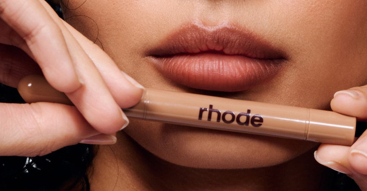 model holding a peptide lip shape below her lips